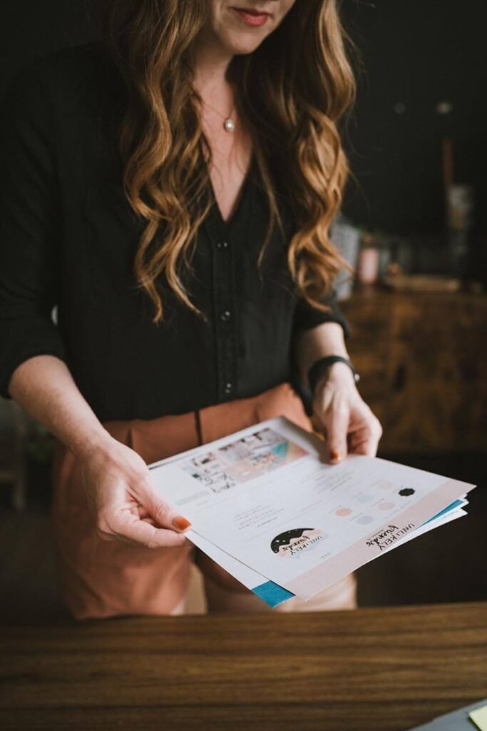 woman with long red hair holding branding identity paperwork with company logos