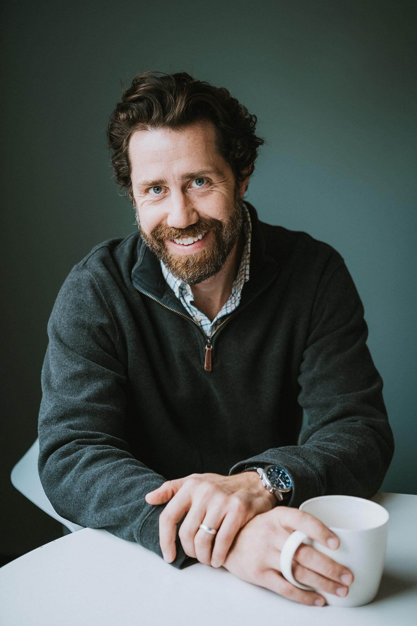 Man holding coffee and looking at camera while smiling