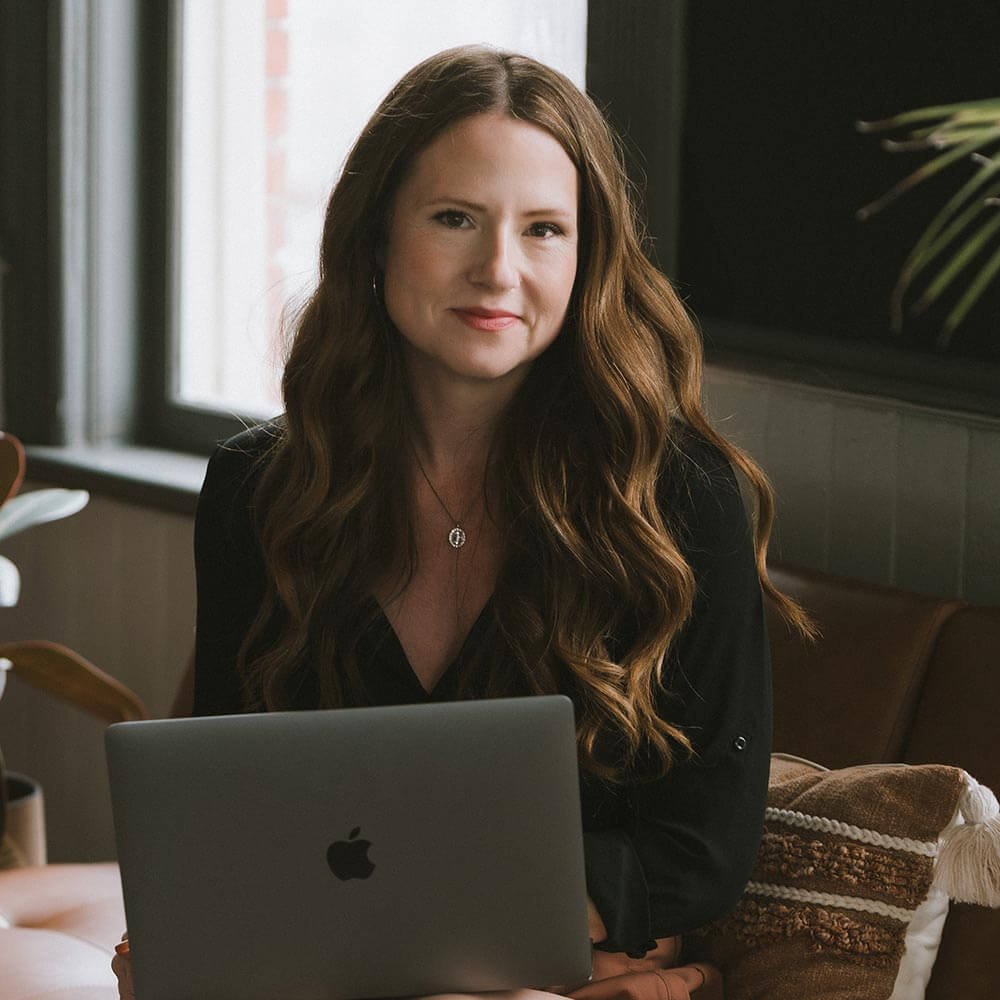 Redhead woman sitting at laptop and smiling into camera